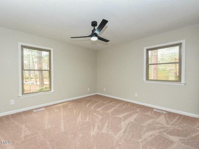 carpeted empty room featuring visible vents, plenty of natural light, and baseboards