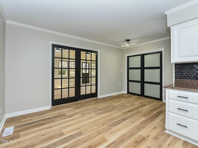 unfurnished dining area featuring crown molding, baseboards, visible vents, and light wood finished floors