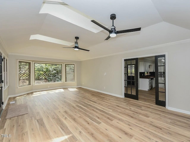 unfurnished living room with a ceiling fan, baseboards, light wood finished floors, a tray ceiling, and crown molding