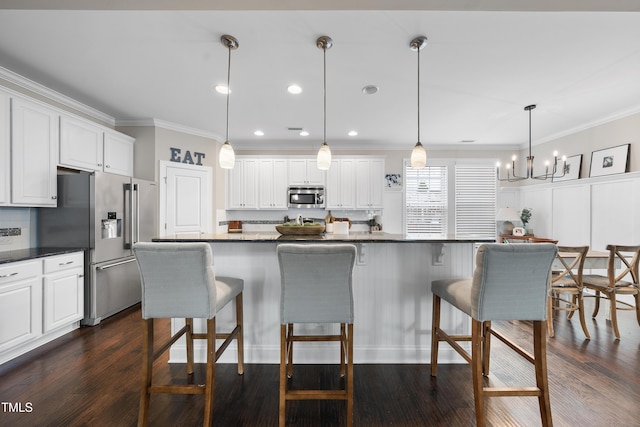 kitchen featuring dark countertops, a breakfast bar area, stainless steel appliances, and crown molding