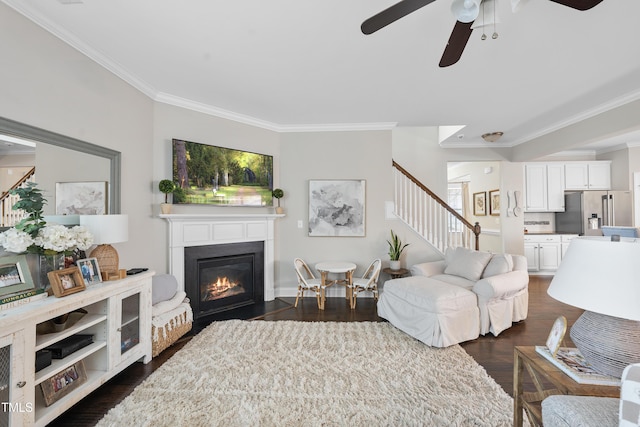 living room with a fireplace with flush hearth, dark wood-style flooring, stairs, and ornamental molding