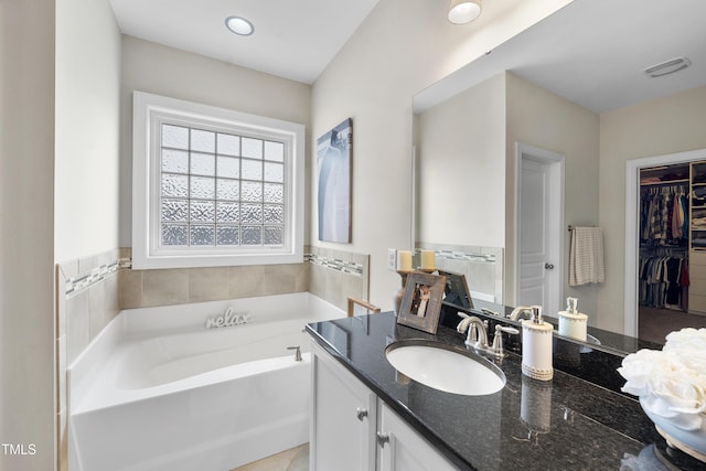 full bath with vanity, a spacious closet, a bath, and visible vents