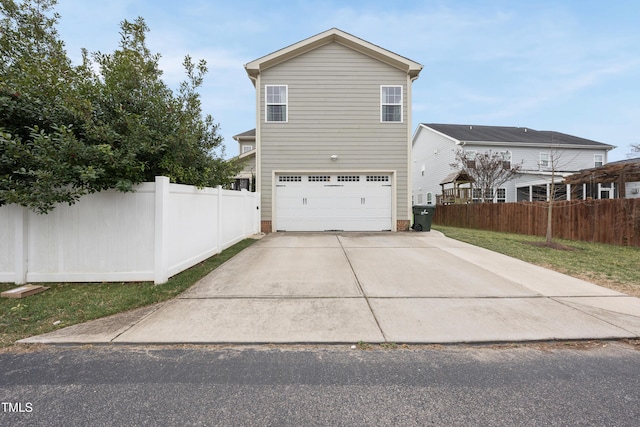 view of home's exterior featuring fence, a garage, and driveway