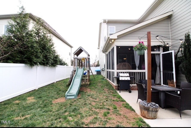 view of yard with a patio area, a playground, fence, and a sunroom