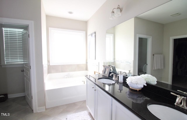 full bathroom with tile patterned flooring, a garden tub, double vanity, and a sink