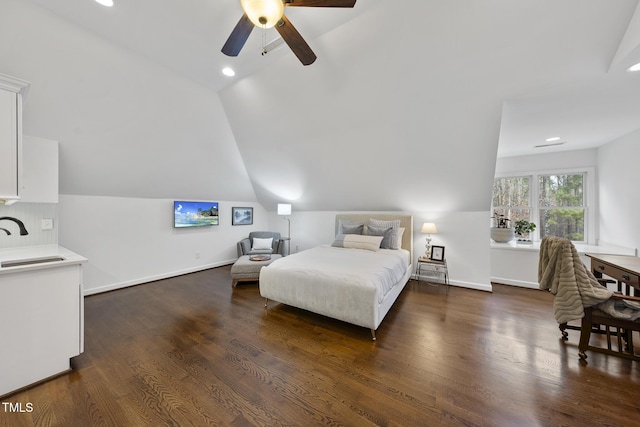 bedroom with dark wood finished floors, vaulted ceiling, baseboards, and a sink