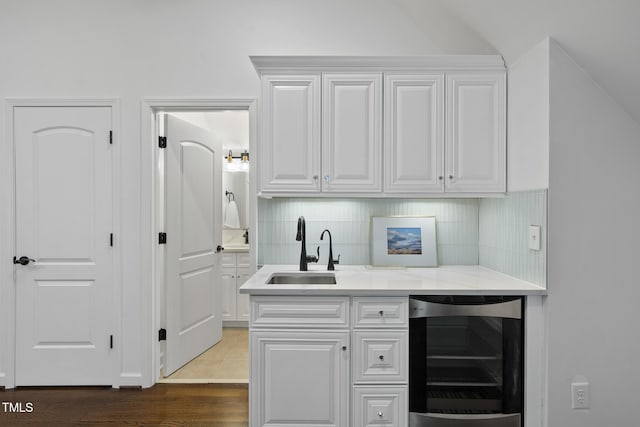 bar featuring a sink, wood finished floors, tasteful backsplash, and beverage cooler