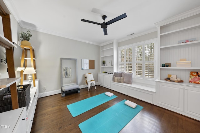 exercise area featuring a ceiling fan, baseboards, visible vents, dark wood-style flooring, and ornamental molding