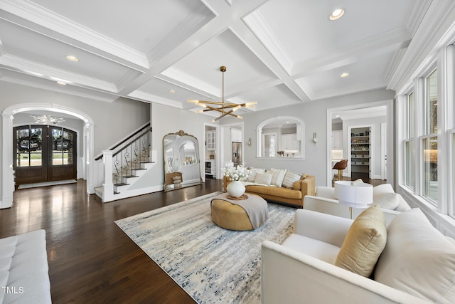 living area with french doors, an inviting chandelier, beamed ceiling, and stairs