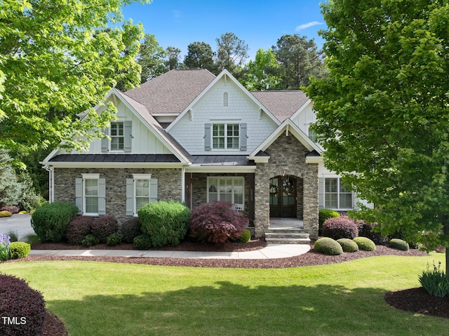 craftsman-style home with a standing seam roof, a front lawn, board and batten siding, and a shingled roof