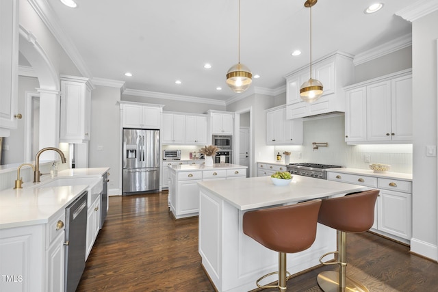 kitchen featuring a sink, a kitchen island, dark wood-style floors, stainless steel appliances, and white cabinets