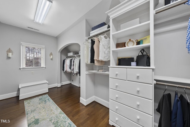 walk in closet featuring dark wood finished floors, arched walkways, and visible vents