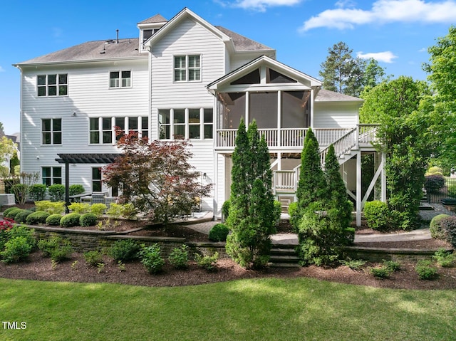 back of property featuring stairway, a lawn, a pergola, and a sunroom