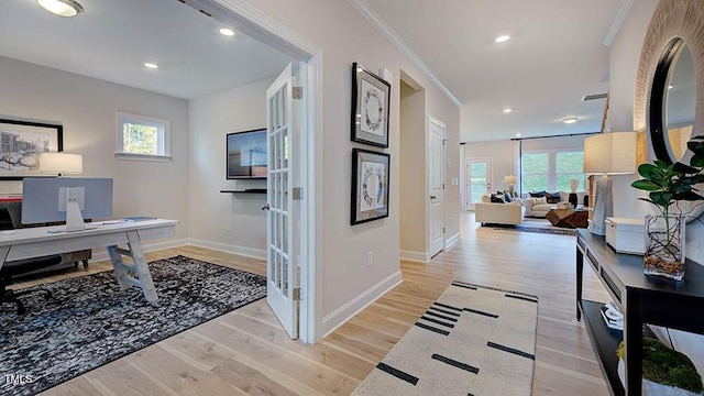 corridor with light wood-style flooring, plenty of natural light, and ornamental molding