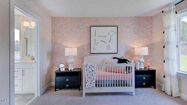 carpeted bedroom with ensuite bath, wallpapered walls, baseboards, and a sink