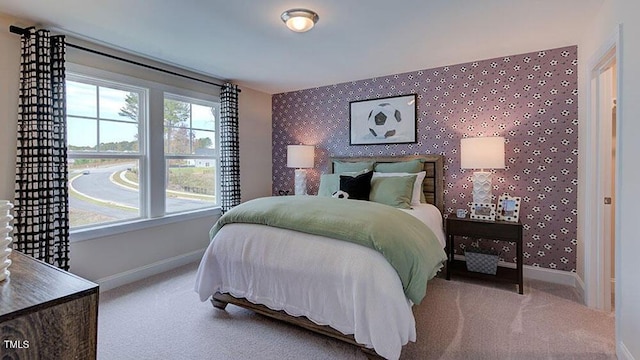 carpeted bedroom with wallpapered walls, an accent wall, and baseboards