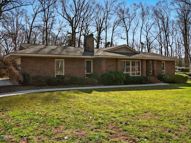 view of front of home featuring brick siding, a chimney, and a front lawn