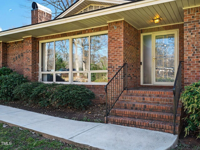 doorway to property with brick siding and a chimney