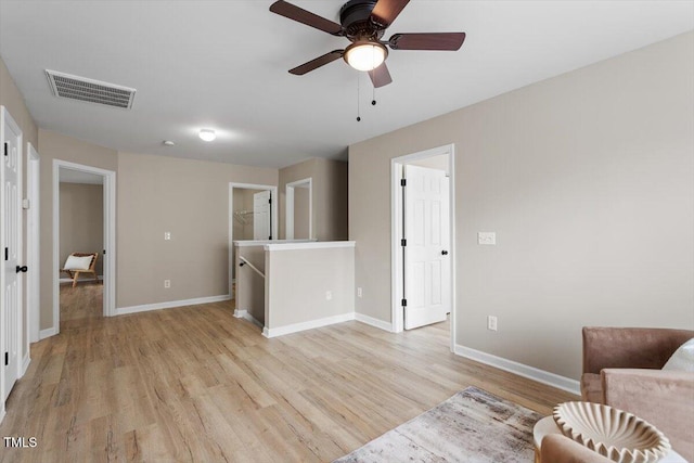 living area with visible vents, light wood-style flooring, baseboards, and ceiling fan