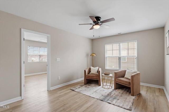 sitting room featuring light wood-type flooring, visible vents, baseboards, and a healthy amount of sunlight