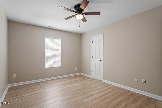 empty room featuring a ceiling fan, light wood-style flooring, baseboards, and visible vents