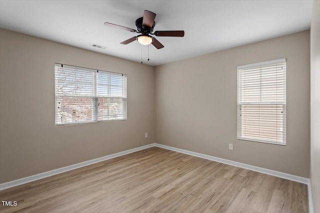 empty room featuring light wood finished floors, visible vents, ceiling fan, and baseboards