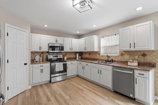 kitchen featuring a sink, stainless steel appliances, light wood-type flooring, and white cabinetry