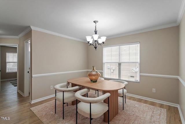 dining room featuring light wood finished floors, an inviting chandelier, crown molding, and baseboards