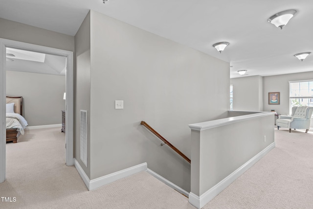 corridor featuring baseboards, an upstairs landing, and carpet flooring