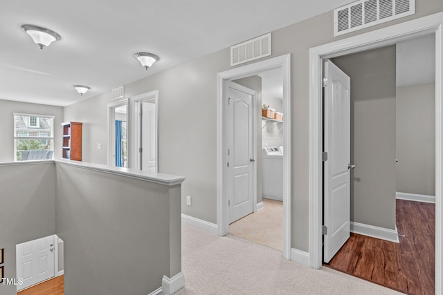 corridor featuring visible vents, light carpet, and baseboards