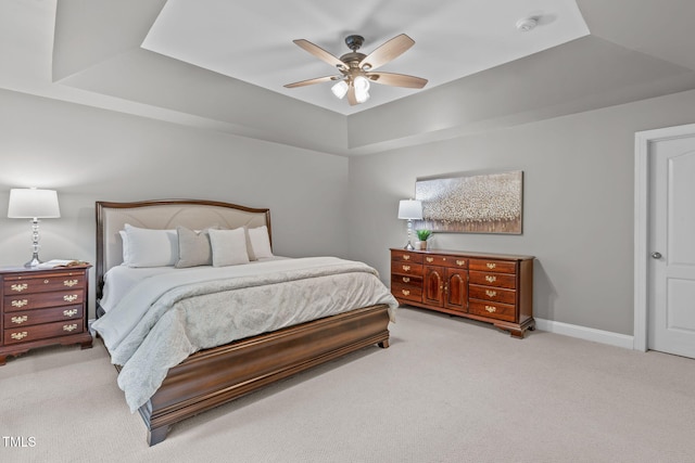 carpeted bedroom with a tray ceiling, baseboards, and ceiling fan