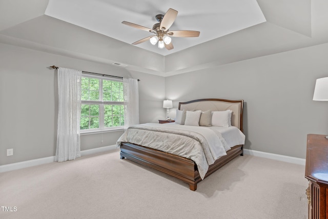 carpeted bedroom with visible vents, a ceiling fan, a raised ceiling, and baseboards