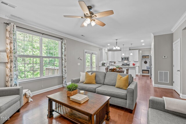 living area featuring visible vents, wood finished floors, and crown molding