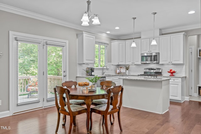 dining space featuring crown molding, recessed lighting, wood finished floors, and a chandelier