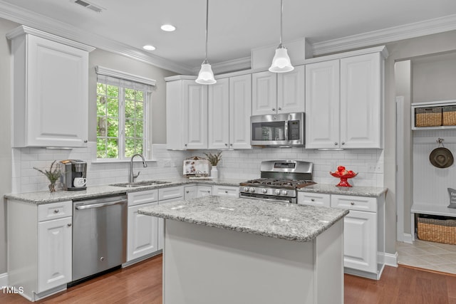 kitchen with white cabinetry, crown molding, appliances with stainless steel finishes, and a sink