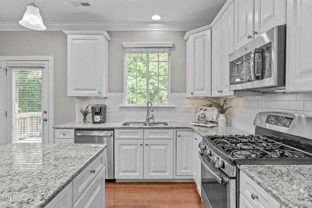 kitchen featuring a sink, appliances with stainless steel finishes, white cabinets, and crown molding