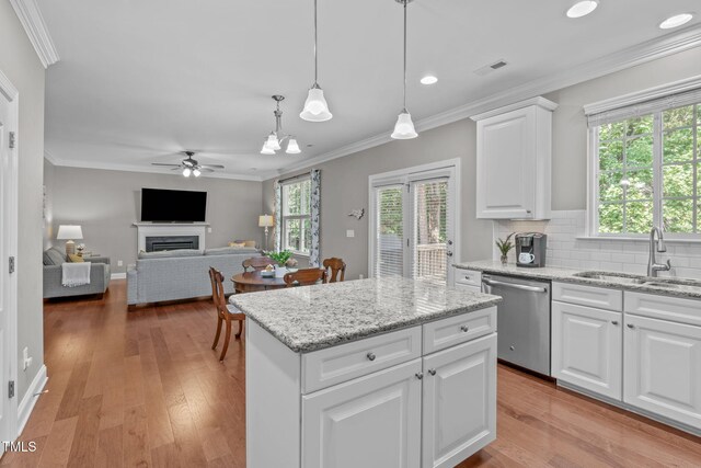 kitchen featuring visible vents, light wood-style flooring, a fireplace, stainless steel dishwasher, and a sink