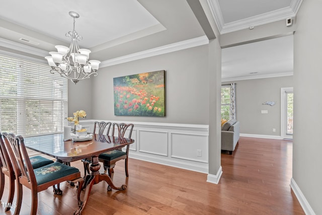 dining area with visible vents, light wood finished floors, ornamental molding, a raised ceiling, and a chandelier