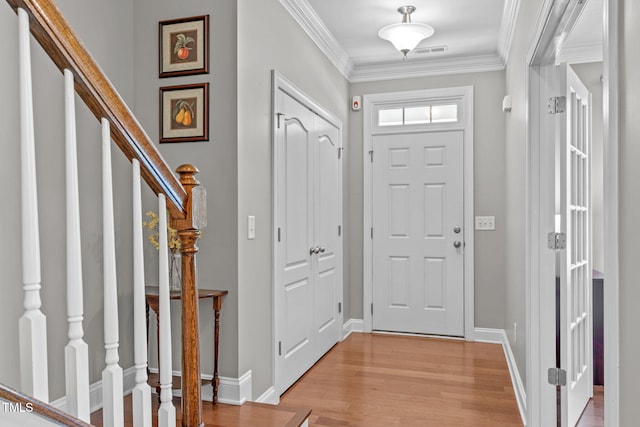 entrance foyer with stairway, baseboards, visible vents, light wood finished floors, and ornamental molding