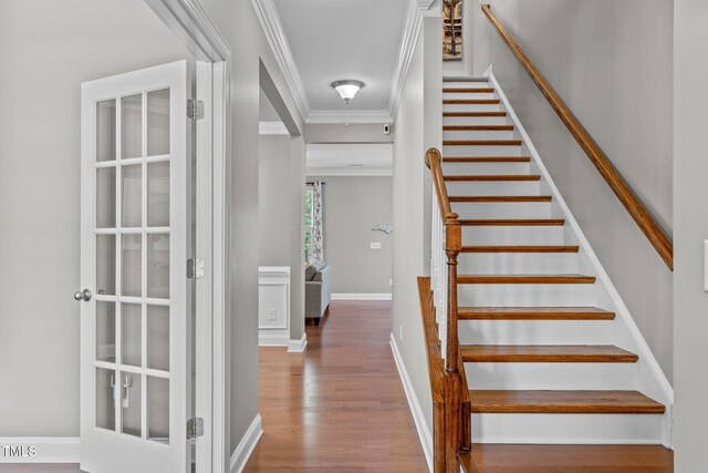 stairway featuring wood finished floors, baseboards, and ornamental molding