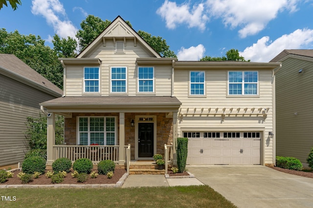 view of front of house featuring stone siding, driveway, covered porch, and an attached garage