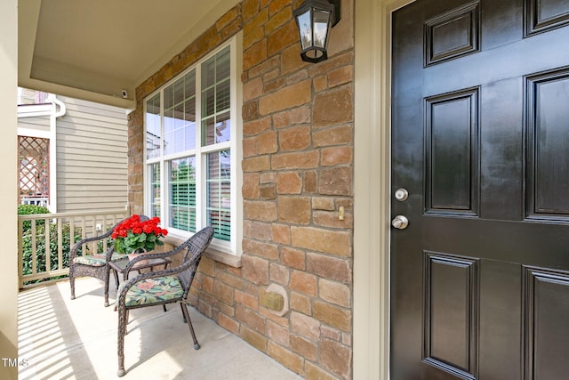 view of exterior entry with brick siding and covered porch