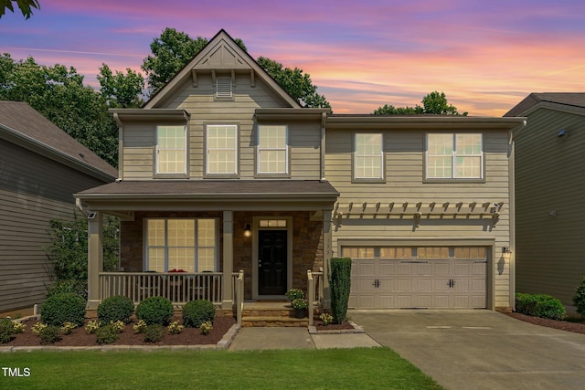 view of front of house featuring stone siding, covered porch, driveway, and a garage