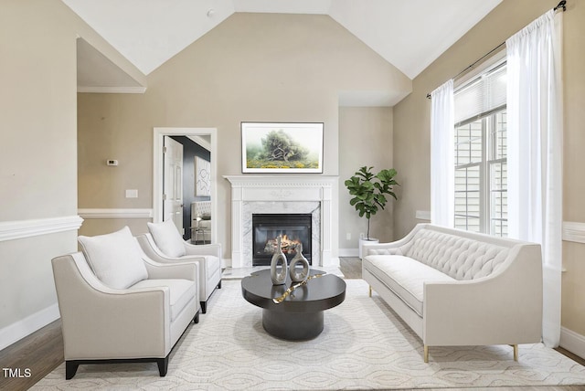 living area featuring vaulted ceiling, wood finished floors, a fireplace, and baseboards