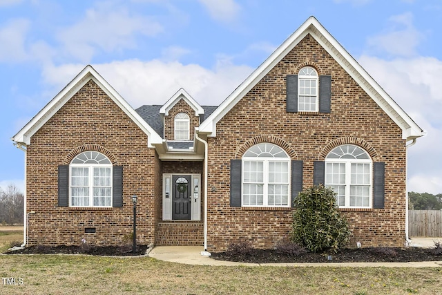 traditional-style house with crawl space, a front yard, brick siding, and fence