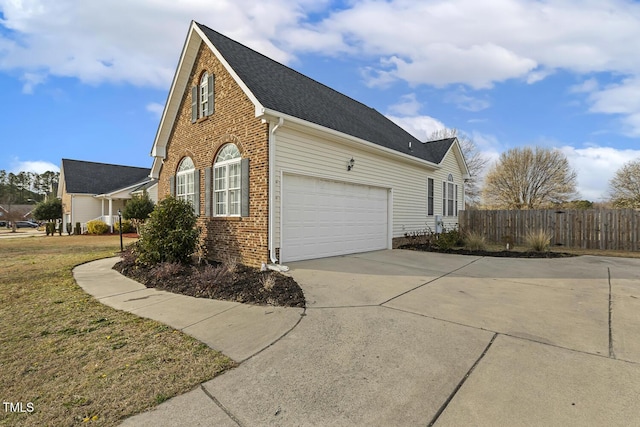 view of side of property with fence, driveway, an attached garage, a yard, and brick siding