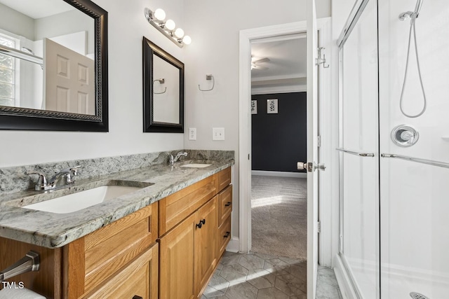 bathroom with double vanity, a stall shower, crown molding, and a sink