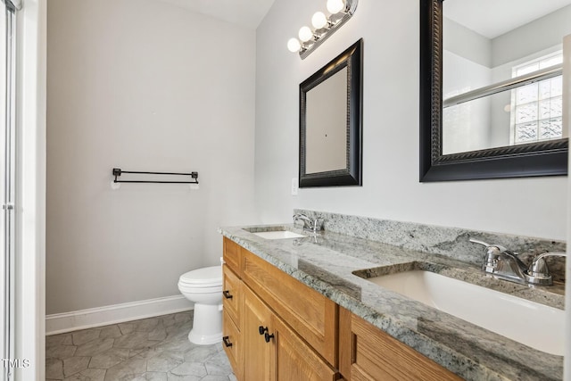 full bath with double vanity, toilet, baseboards, and a sink