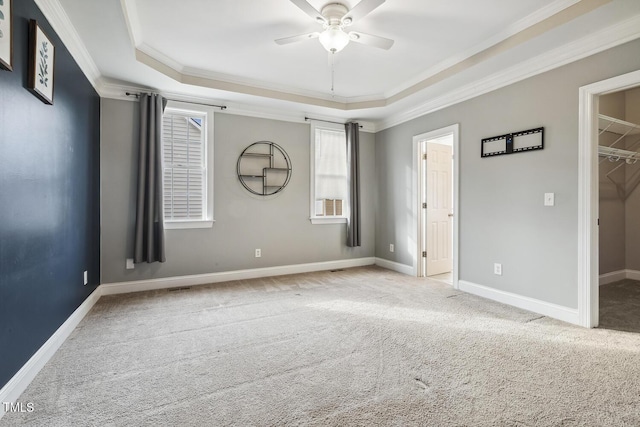 spare room featuring baseboards, carpet, ornamental molding, a raised ceiling, and a ceiling fan