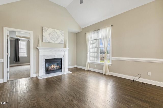 unfurnished living room with baseboards, lofted ceiling, wood finished floors, and a fireplace